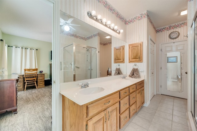 full bathroom featuring a sink, ceiling fan, a stall shower, and wallpapered walls