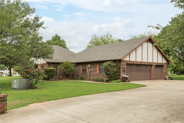 tudor house with a garage, a shingled roof, concrete driveway, and a front yard