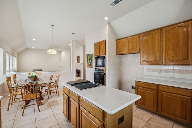 kitchen with light countertops, brown cabinetry, vaulted ceiling, visible vents, and black appliances