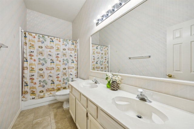 bathroom with a sink, toilet, wallpapered walls, and double vanity