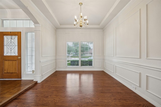 foyer entrance with an inviting chandelier, a decorative wall, and dark wood-style floors