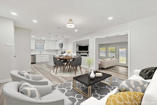 living area with light wood-style floors, recessed lighting, and baseboards