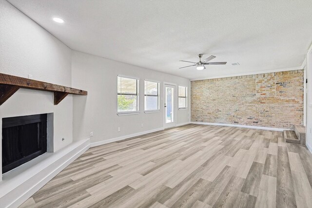 unfurnished living room with light wood-style floors, a fireplace with raised hearth, visible vents, baseboards, and a ceiling fan