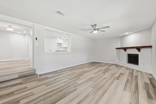 unfurnished living room featuring a fireplace, light wood-style floors, ceiling fan, visible vents, and baseboards