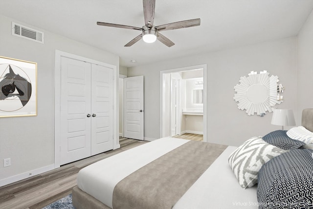 bedroom with visible vents, ensuite bathroom, a closet, baseboards, and wood finished floors