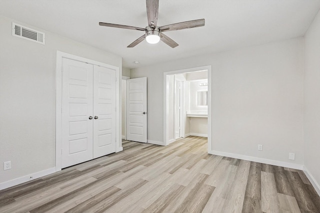 unfurnished bedroom featuring wood finished floors, ensuite bath, a closet, baseboards, and visible vents