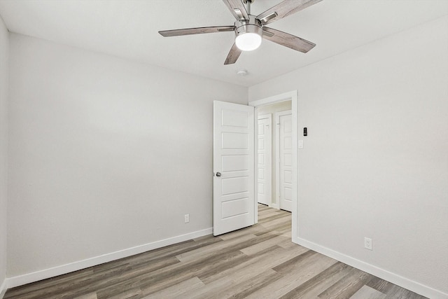 empty room featuring light wood-type flooring, a ceiling fan, and baseboards
