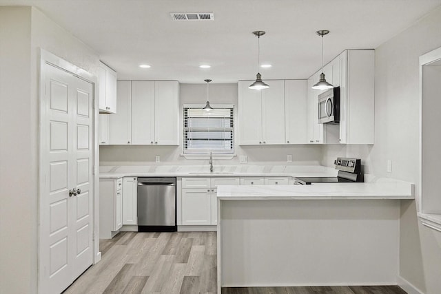 kitchen featuring white cabinets, a sink, appliances with stainless steel finishes, visible vents, and a peninsula