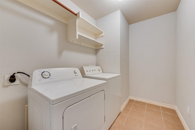 laundry room with light tile patterned floors, washer and clothes dryer, laundry area, and baseboards