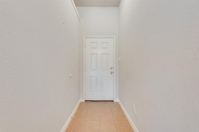 hallway featuring baseboards and light tile patterned floors
