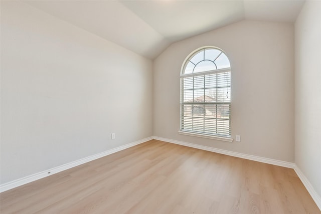empty room featuring baseboards, light wood-style floors, and lofted ceiling