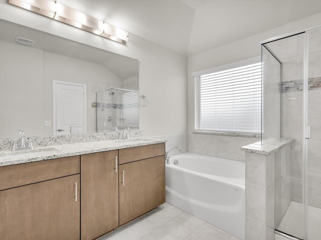 bathroom featuring double vanity, a garden tub, a stall shower, and a sink