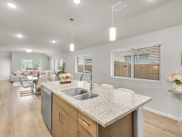 kitchen featuring a sink, decorative light fixtures, open floor plan, and light wood-style floors