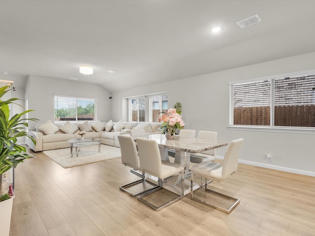 dining space with visible vents, baseboards, lofted ceiling, and light wood-style floors