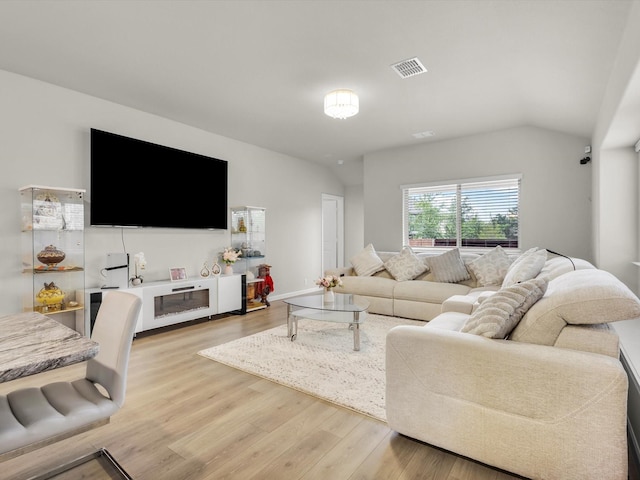 living room featuring visible vents, lofted ceiling, and light wood-type flooring