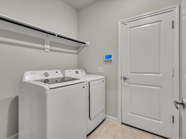 washroom with light tile patterned floors, washing machine and clothes dryer, laundry area, and baseboards