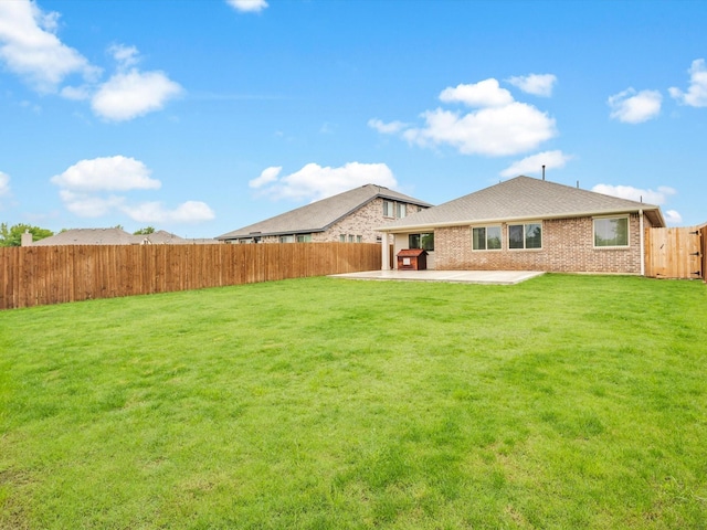 back of house with brick siding, a fenced backyard, a yard, and a patio area