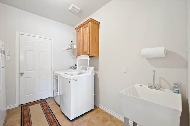 laundry area with cabinet space, a sink, visible vents, light tile patterned flooring, and washing machine and dryer