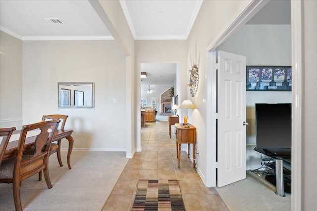 hall featuring baseboards, visible vents, light tile patterned flooring, and crown molding