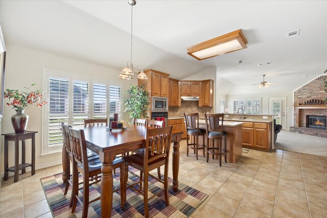 dining room featuring light tile patterned floors, a brick fireplace, lofted ceiling, and visible vents