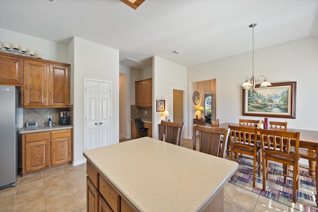 kitchen featuring brown cabinets, decorative backsplash, freestanding refrigerator, and light countertops