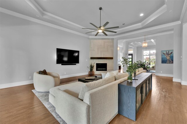 living room featuring baseboards, a ceiling fan, a raised ceiling, and wood finished floors