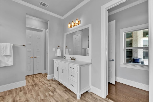 bathroom featuring crown molding, vanity, baseboards, wood finished floors, and visible vents