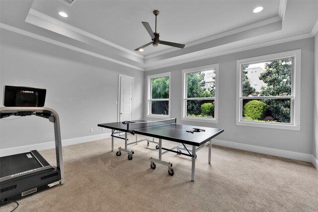recreation room featuring crown molding, a ceiling fan, a raised ceiling, and baseboards