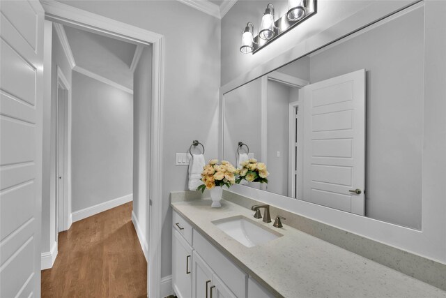 bathroom featuring crown molding, baseboards, wood finished floors, and vanity