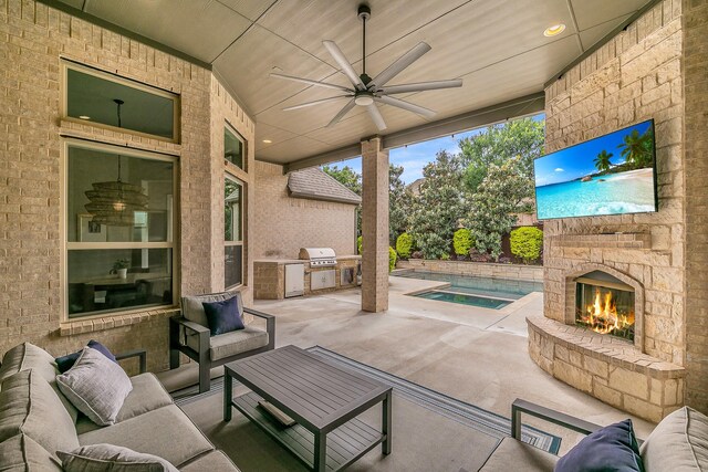 view of patio / terrace featuring area for grilling, exterior kitchen, ceiling fan, and an outdoor living space with a fireplace