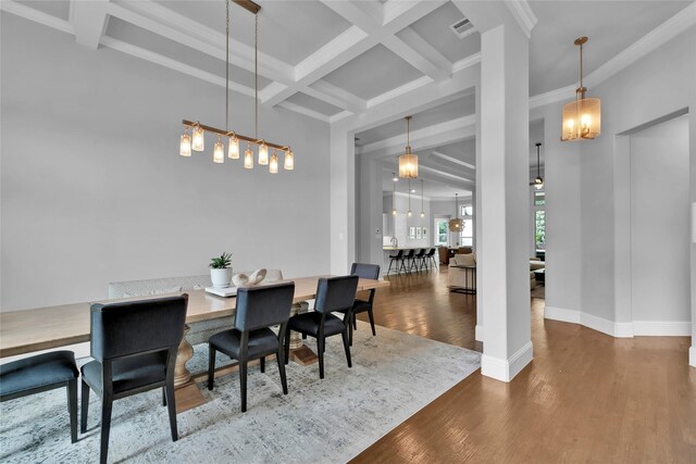 dining space featuring visible vents, wood finished floors, beam ceiling, ornamental molding, and coffered ceiling