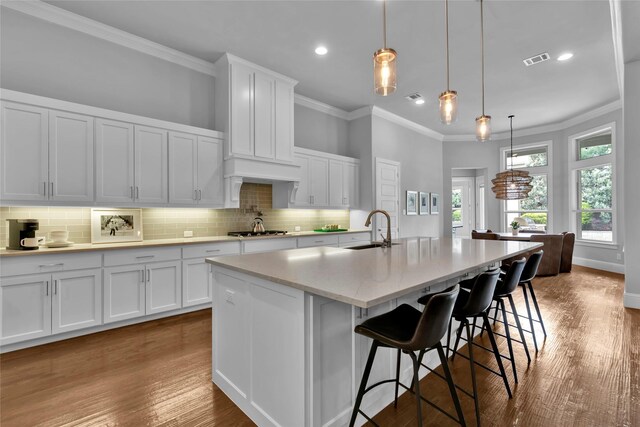 kitchen featuring crown molding, a sink, stainless steel gas stovetop, backsplash, and visible vents