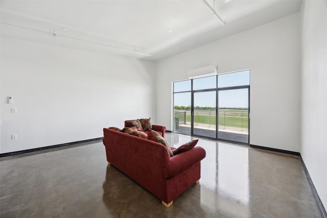 living room featuring baseboards, a wall mounted air conditioner, and concrete flooring