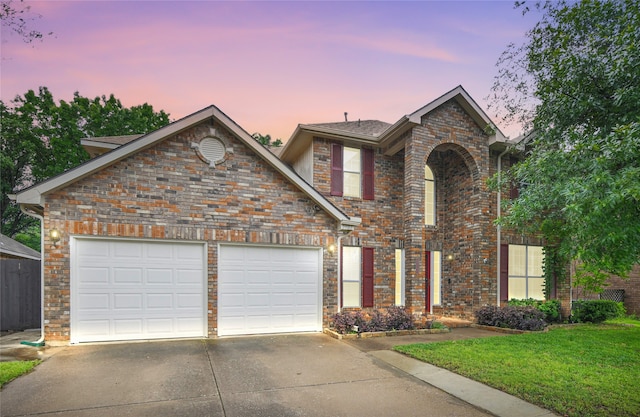traditional-style home featuring a garage, brick siding, a front lawn, and driveway