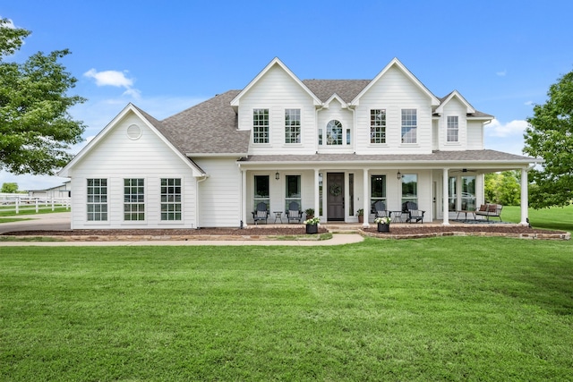 view of front of house with a porch, a front lawn, and roof with shingles