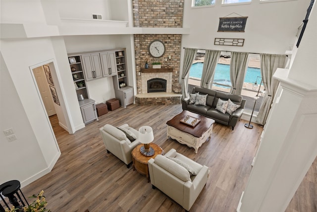 living area with wood finished floors, visible vents, and a high ceiling