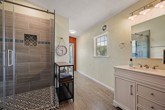 full bath featuring baseboards, wood finished floors, a shower stall, and vanity