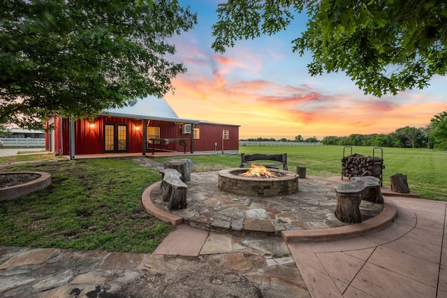 patio terrace at dusk featuring a yard, french doors, and an outdoor fire pit