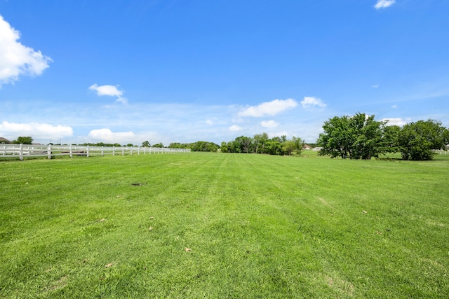 view of yard with fence and a rural view