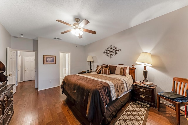 bedroom featuring a textured ceiling, visible vents, ceiling fan, hardwood / wood-style floors, and baseboards