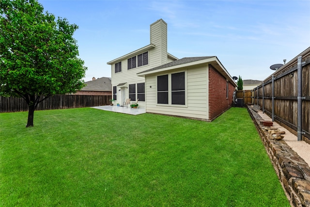 rear view of house featuring a patio, a yard, a fenced backyard, and a chimney