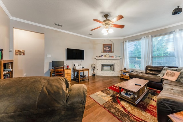 living area with crown molding, visible vents, ceiling fan, and wood finished floors