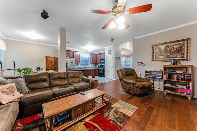 living area featuring dark wood finished floors, ornamental molding, and ceiling fan