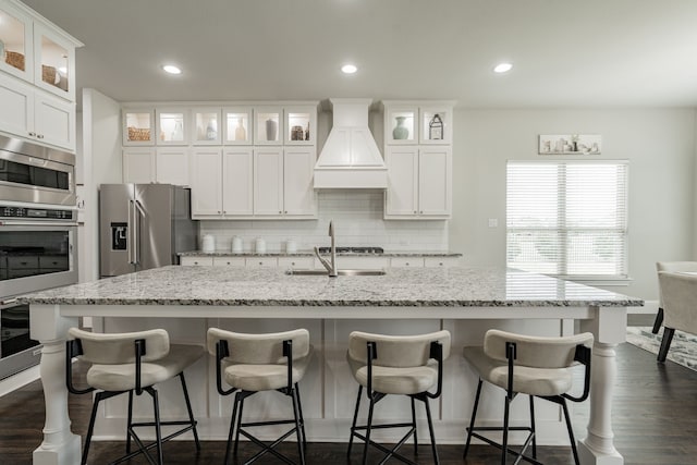 505 Eloise Dr, Heath, TX 75032 - kitchen with custom exhaust hood, white cabinets, backsplash, a sink, and a center island with sink
