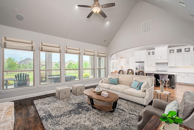 living room featuring arched walkways, a ceiling fan, wood finished floors, and visible vents