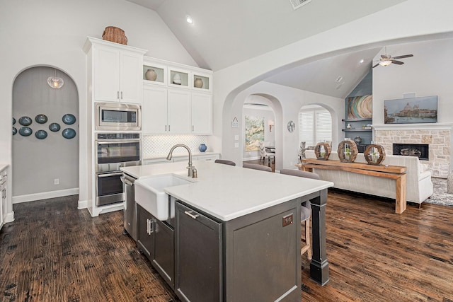 kitchen featuring a sink, white cabinetry, a ceiling fan, appliances with stainless steel finishes, and vaulted ceiling