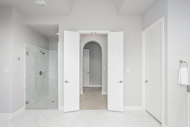 bathroom featuring baseboards, marble finish floor, and a stall shower