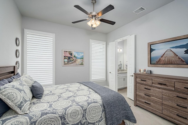 bedroom with visible vents, connected bathroom, ceiling fan, and light colored carpet