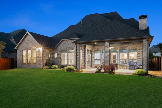 back of property featuring a fenced backyard, a chimney, a patio area, and brick siding