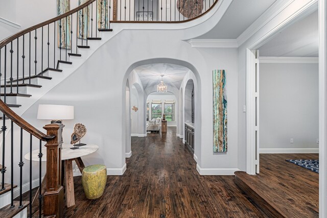 entrance foyer featuring stairway, arched walkways, baseboards, and wood finished floors